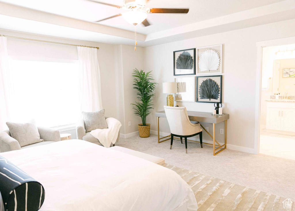 Carpeted bedroom with ceiling fan, connected bathroom, and a tray ceiling