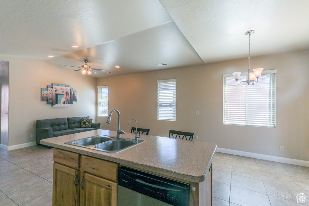 Kitchen with an island with sink, sink, light tile floors, dishwasher, and ceiling fan with notable chandelier