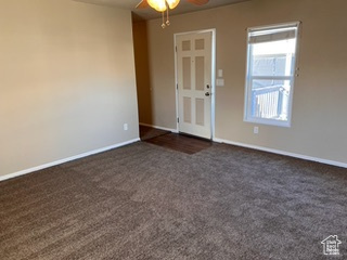 Unfurnished room featuring dark carpet and ceiling fan