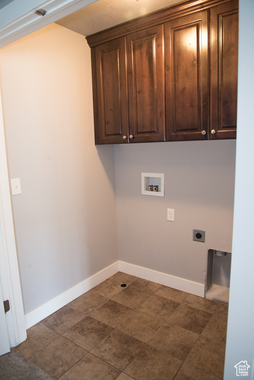 Laundry area featuring washer hookup, dark tile floors, hookup for an electric dryer, and cabinets