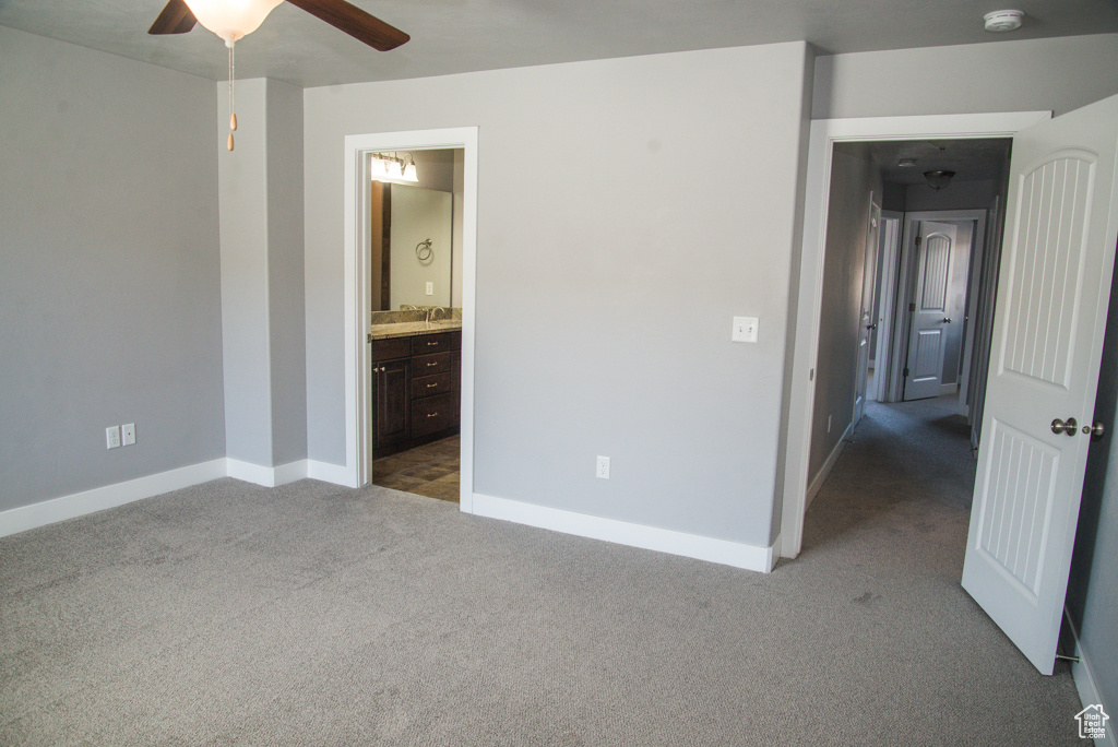Unfurnished bedroom featuring dark colored carpet, ceiling fan, and ensuite bathroom