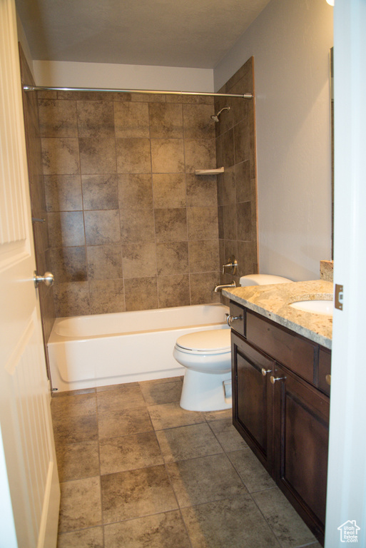 Full bathroom with vanity, tiled shower / bath combo, tile flooring, and toilet