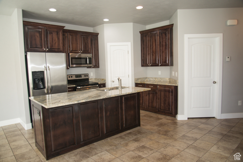 Kitchen featuring light stone countertops, stainless steel appliances, light tile floors, and sink