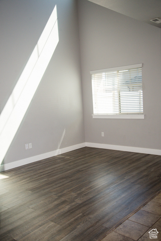 Empty room featuring dark hardwood / wood-style flooring and lofted ceiling