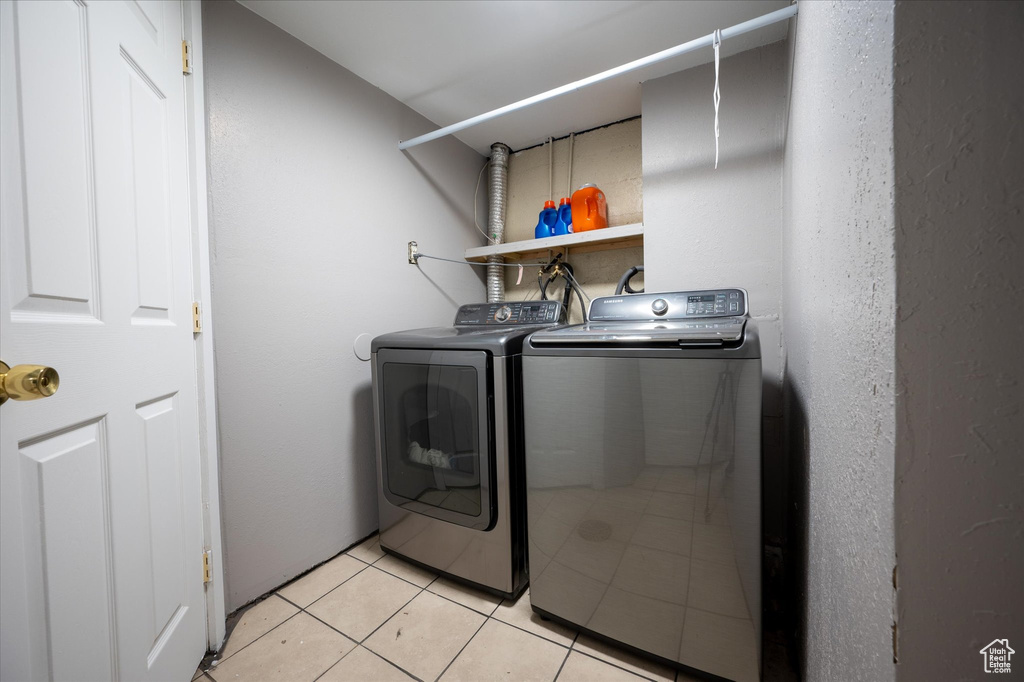 Laundry room featuring separate washer and dryer and light tile floors
