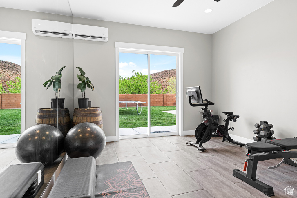 Workout area featuring a wall mounted AC, ceiling fan, and light tile flooring