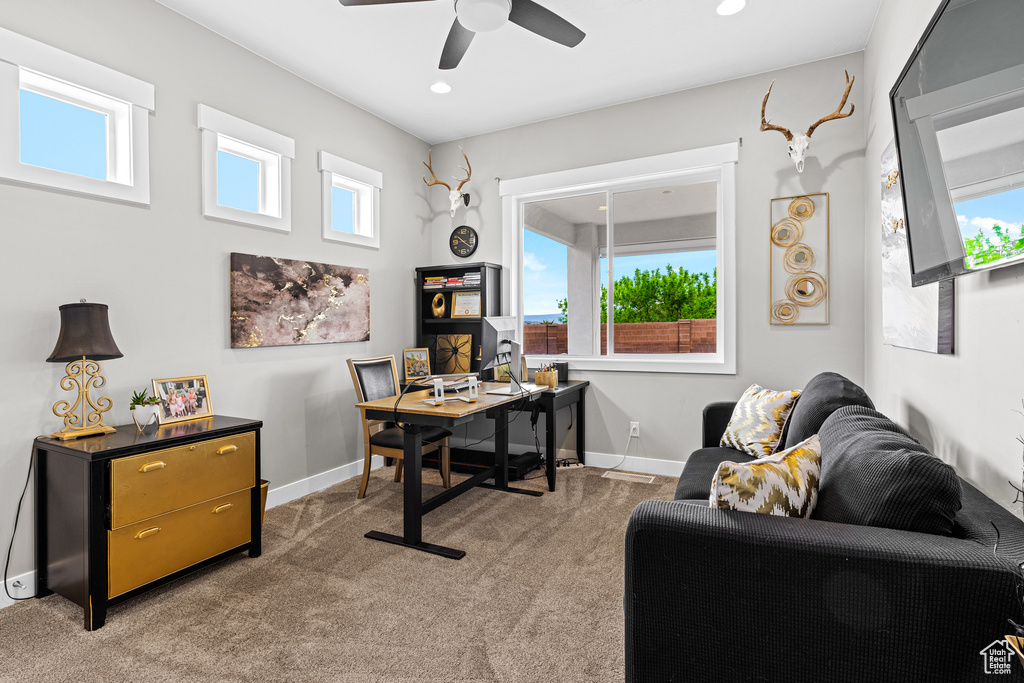 Carpeted office space featuring plenty of natural light and ceiling fan
