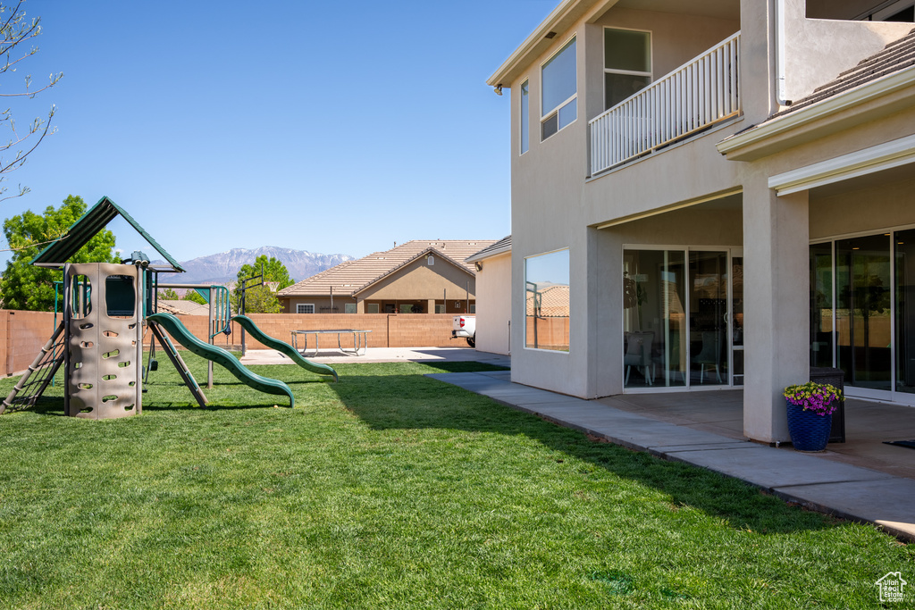 View of yard with a playground, a mountain view, a balcony, and a patio