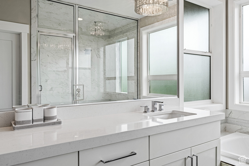Bathroom featuring shower with separate bathtub, plenty of natural light, a notable chandelier, and vanity