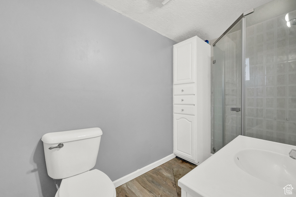 Bathroom with an enclosed shower, hardwood / wood-style floors, vanity, a textured ceiling, and toilet