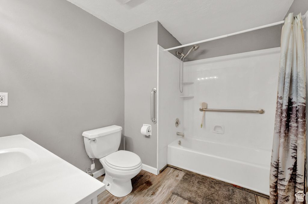 Full bathroom featuring vanity, wood-type flooring, toilet, and shower / bathtub combination with curtain