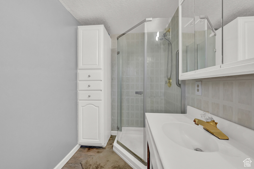 Bathroom with tile floors, a textured ceiling, vanity, and a shower with shower door