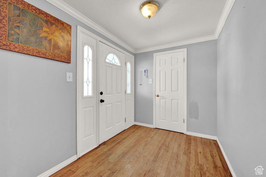 Entrance foyer with light hardwood / wood-style floors and crown molding
