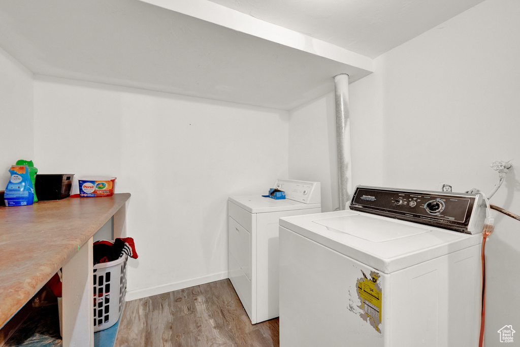 Laundry room with washer and clothes dryer and light hardwood / wood-style flooring