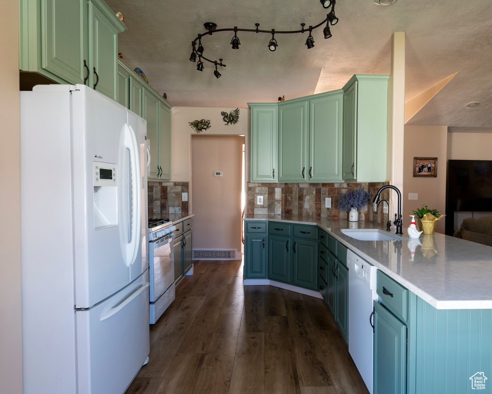 Kitchen with green cabinetry, white appliances, backsplash, dark hardwood / wood-style floors, and sink