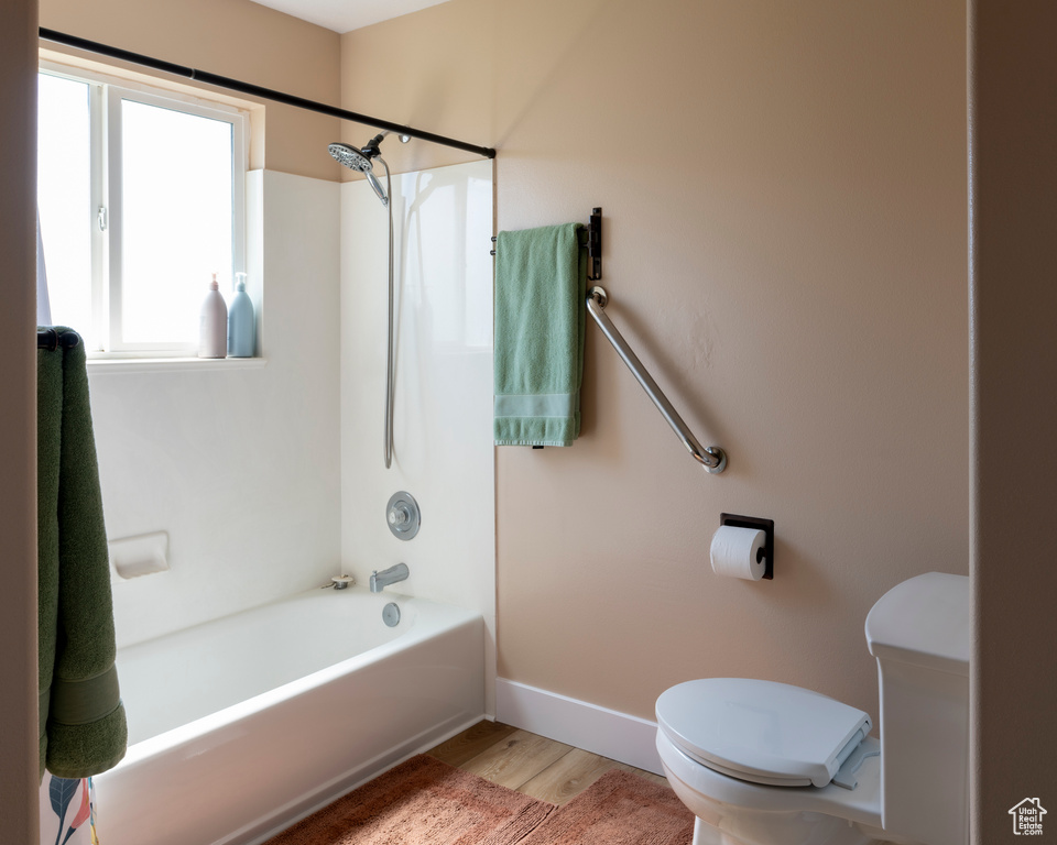 Bathroom with toilet, hardwood / wood-style floors, and shower / bath combination