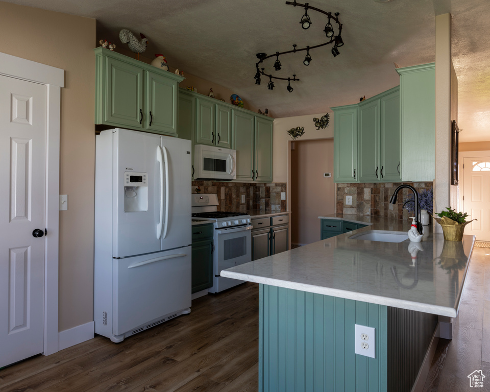 Kitchen with kitchen peninsula, white appliances, backsplash, dark hardwood / wood-style floors, and sink