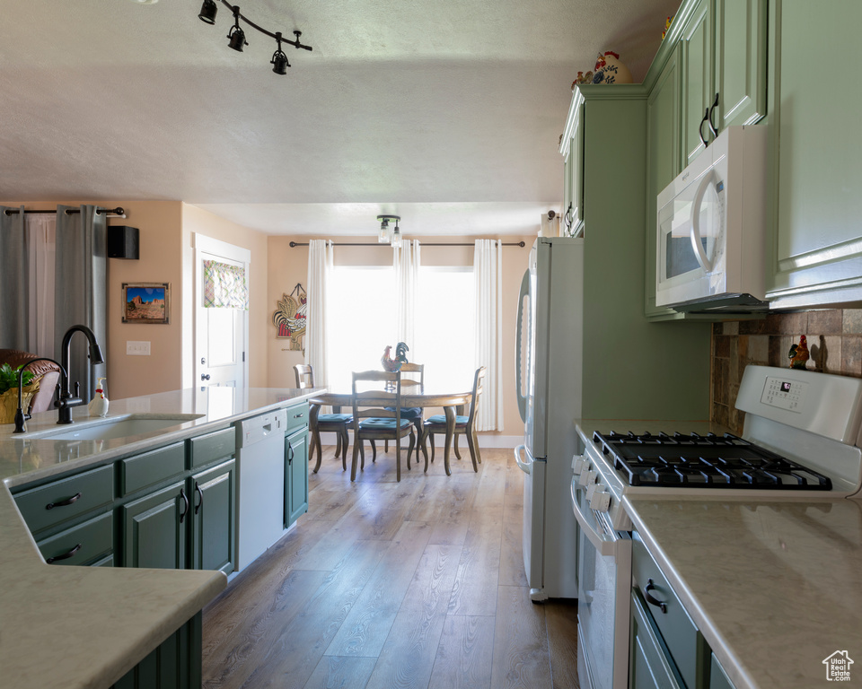 Kitchen featuring green cabinetry, white appliances, sink, light hardwood / wood-style flooring, and tasteful backsplash