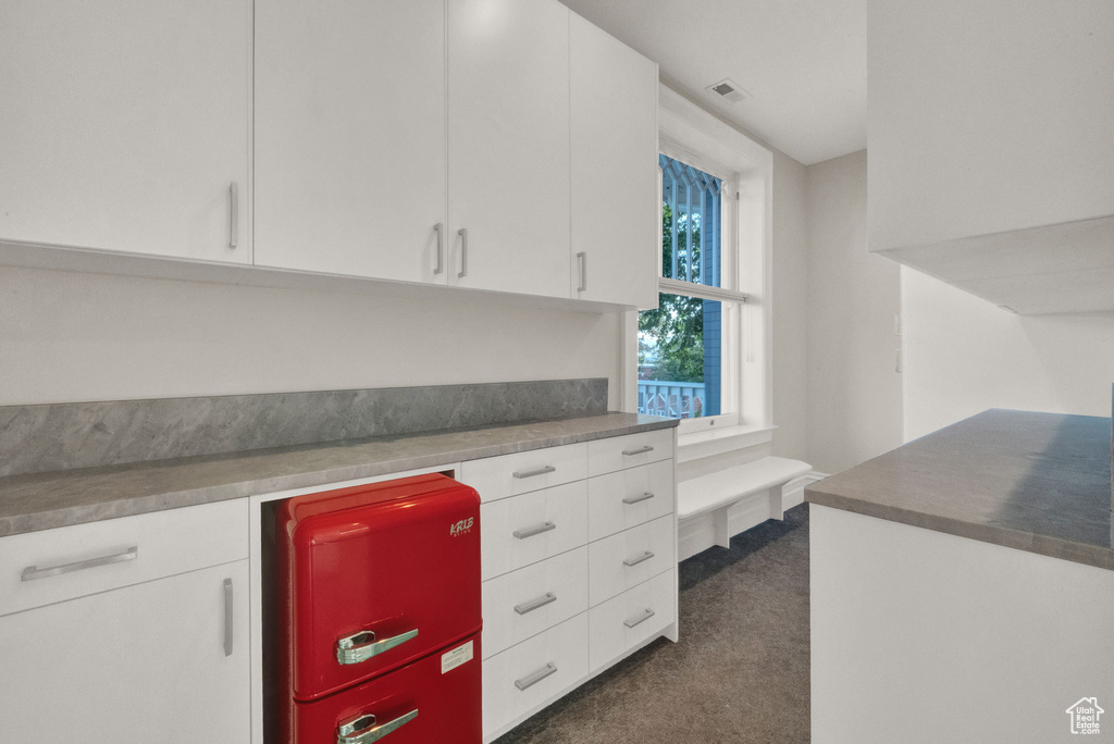 Kitchen featuring white cabinets and dark colored carpet