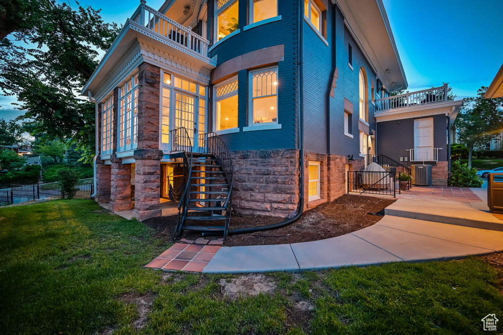 Exterior space with a balcony, central AC unit, and a lawn