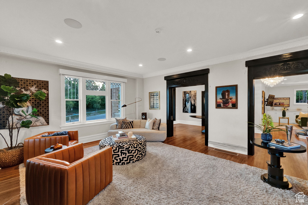 Living room with a chandelier, dark wood-type flooring, and ornamental molding