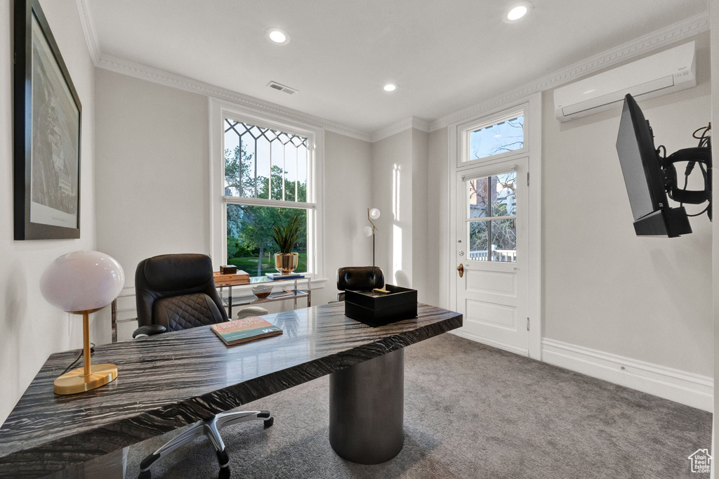 Office space featuring dark colored carpet, a wall mounted air conditioner, crown molding, and a healthy amount of sunlight