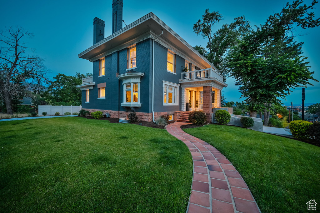 View of front of property featuring a balcony and a yard