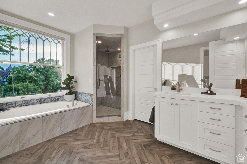Bathroom featuring separate shower and tub, parquet floors, and vanity