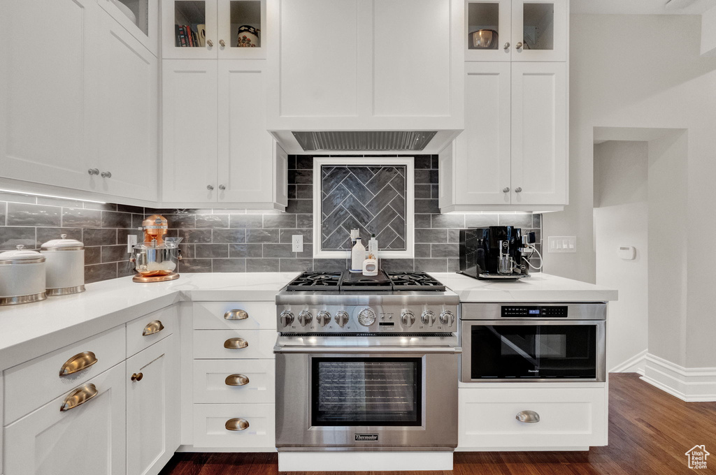 Kitchen with tasteful backsplash, stainless steel appliances, dark hardwood / wood-style floors, and white cabinetry