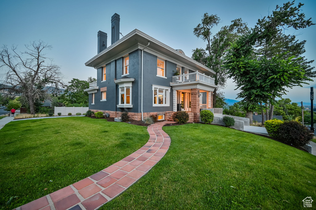 View of front of home featuring a balcony and a front yard