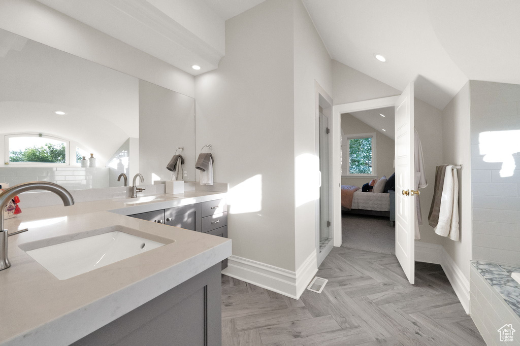 Bathroom featuring walk in shower, parquet flooring, vaulted ceiling, and vanity