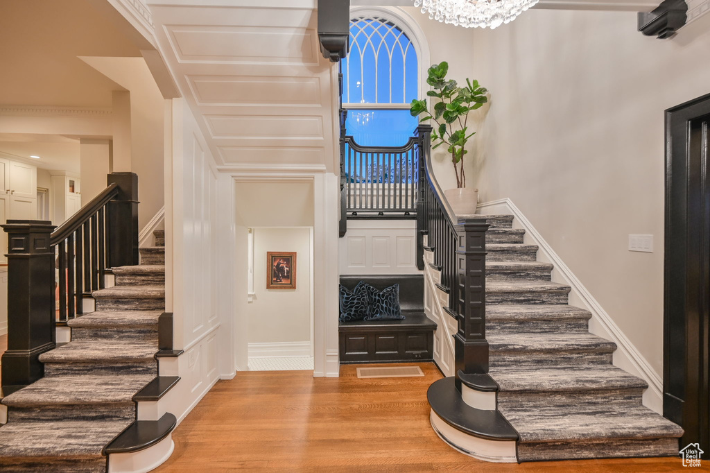 Stairs with light hardwood / wood-style floors and a notable chandelier