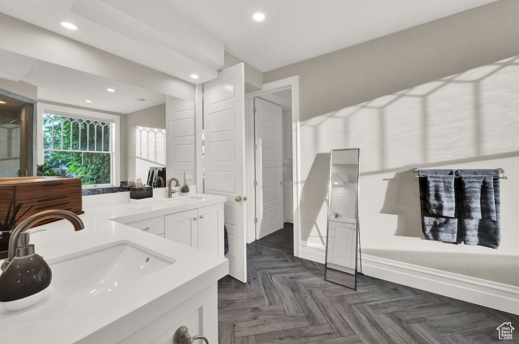 Bathroom with dual sinks, parquet floors, and large vanity