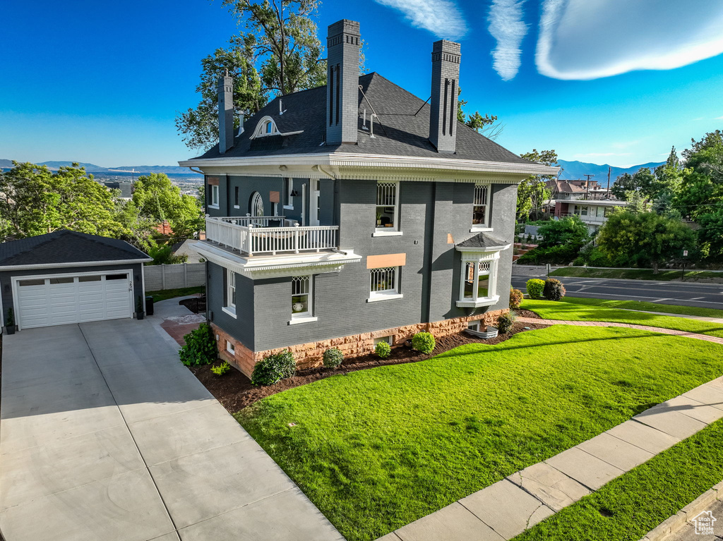 View of front of house featuring a balcony, a front yard, and a garage