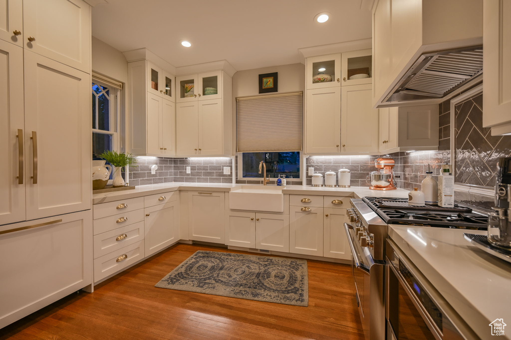 Kitchen with tasteful backsplash, range with two ovens, sink, and dark hardwood / wood-style floors