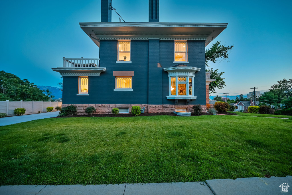 View of front of property with a balcony and a yard