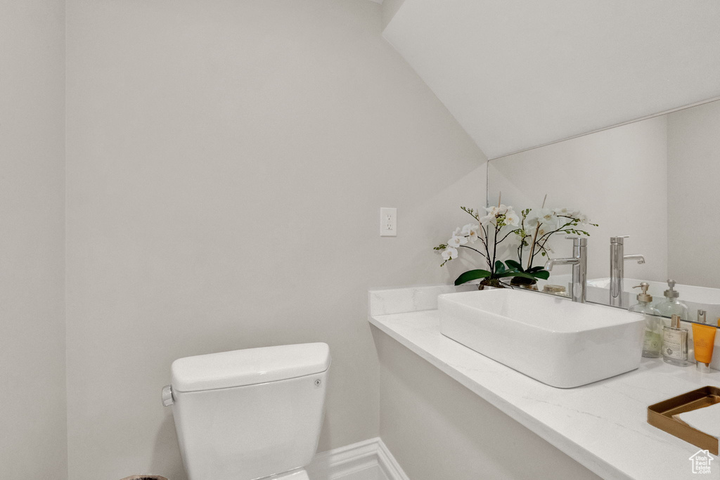 Bathroom with vanity, lofted ceiling, and toilet