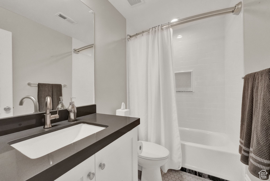 Full bathroom featuring toilet, vanity with extensive cabinet space, tile flooring, and shower / tub combo