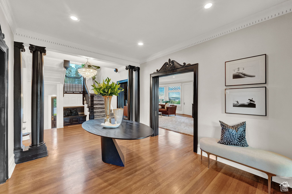 Sitting room with a notable chandelier, crown molding, ornate columns, and light hardwood / wood-style flooring