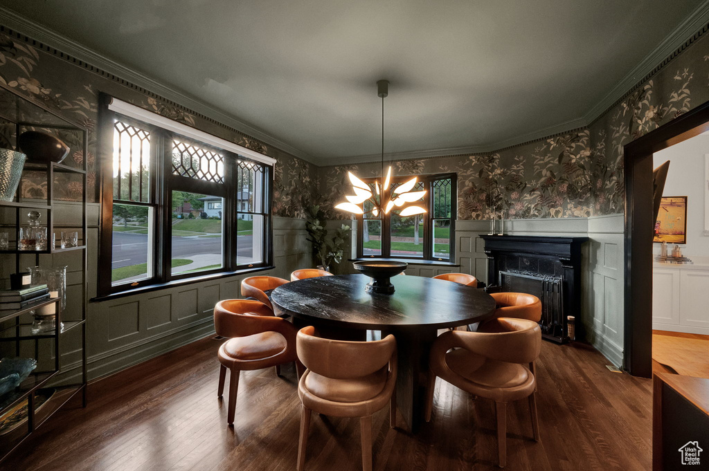 Dining area featuring a notable chandelier, dark wood-type flooring, and crown molding