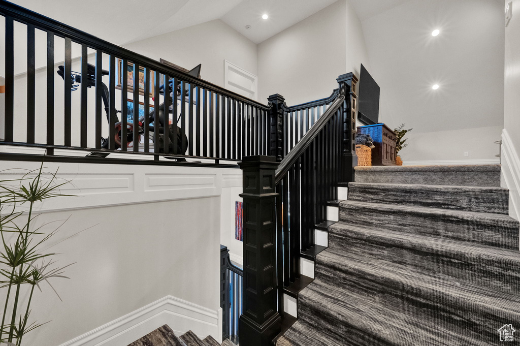 Staircase featuring high vaulted ceiling and dark wood-type flooring