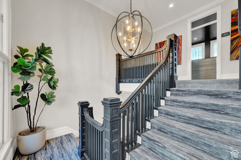 Stairway featuring an inviting chandelier, crown molding, and dark wood-type flooring
