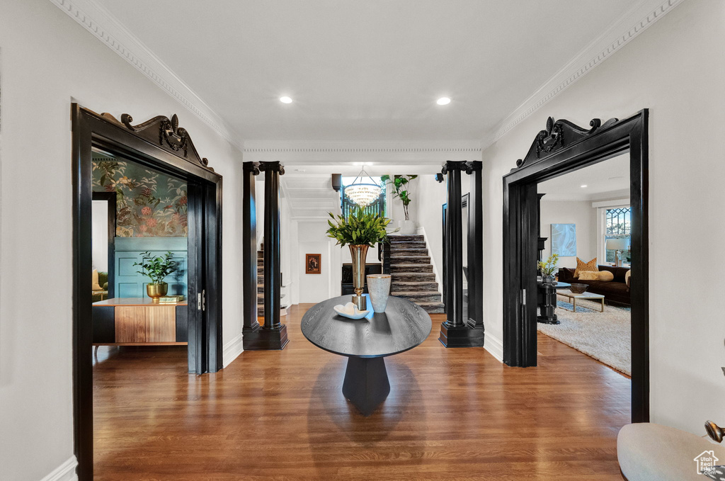 Hallway with an inviting chandelier, dark hardwood / wood-style flooring, and ornamental molding