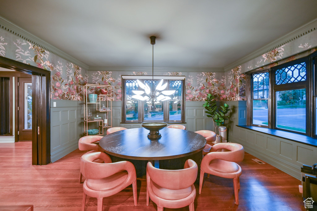 Dining space with a chandelier, wood-type flooring, and crown molding