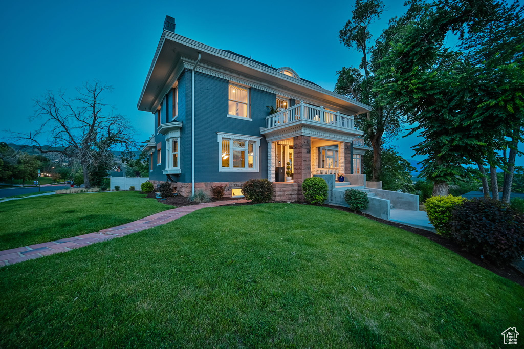 View of front of house featuring a balcony and a yard