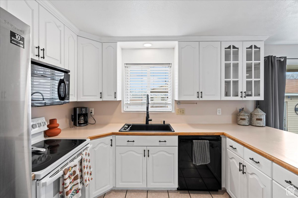 Kitchen with white cabinets, light tile floors, black appliances, and sink