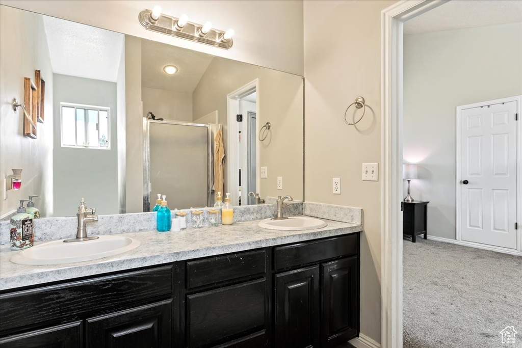 Bathroom featuring oversized vanity, a shower with shower door, and dual sinks