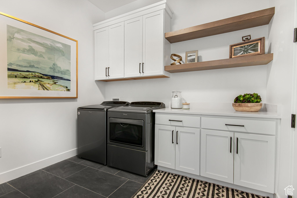 Washroom featuring dark tile floors, independent washer and dryer, and cabinets