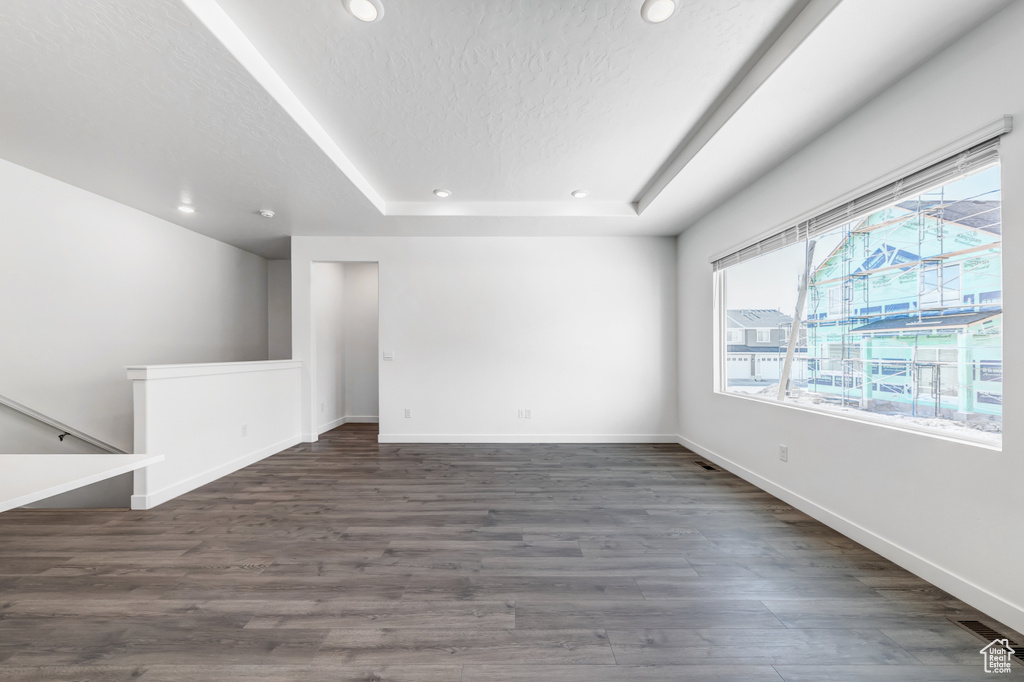 Unfurnished room featuring a tray ceiling and dark wood-type flooring