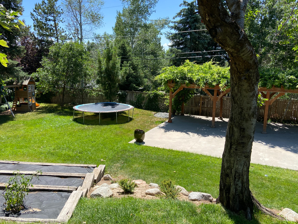 View of yard with a trampoline and a patio area
